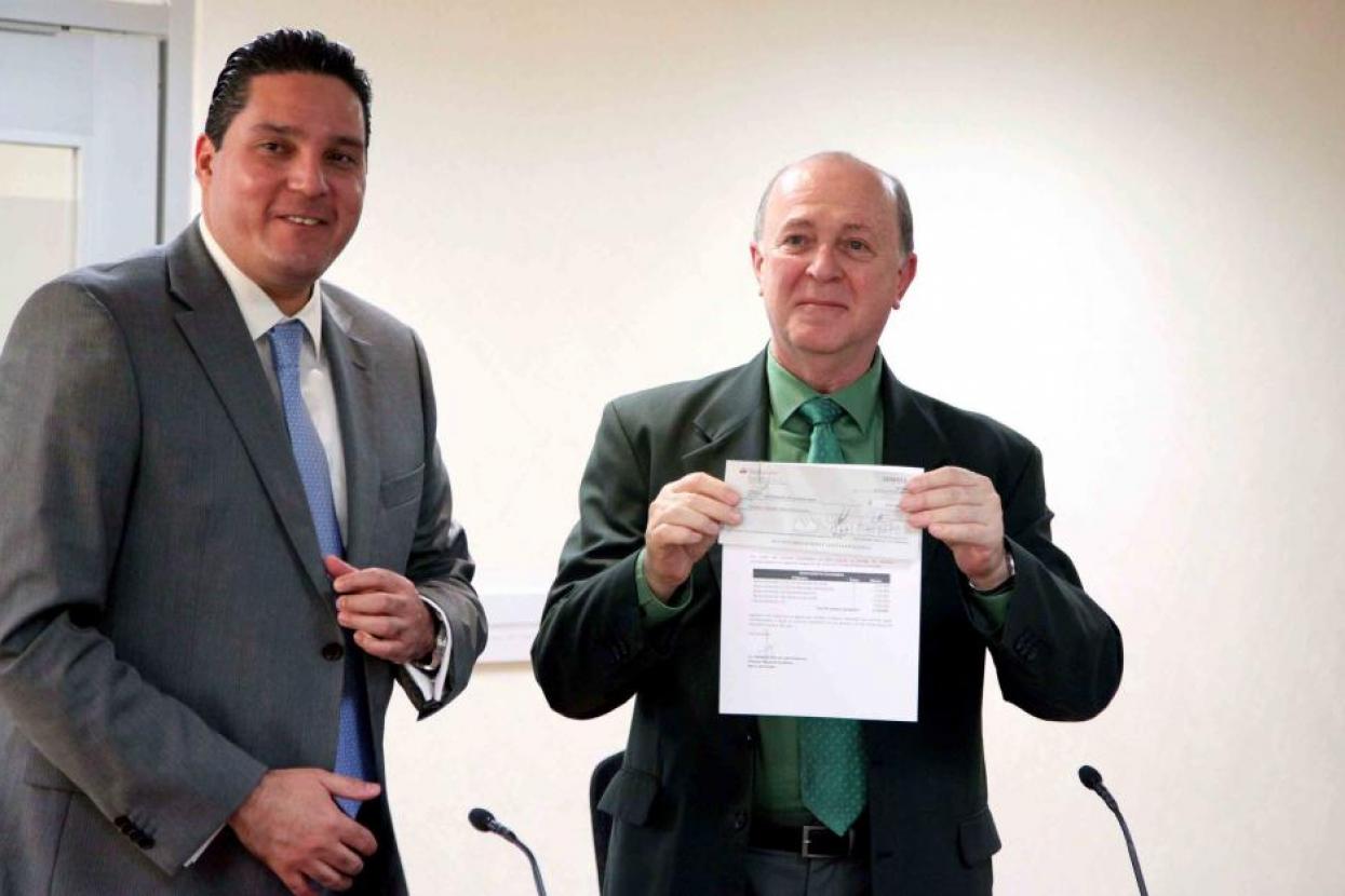 El Vicerrector Ejecutivo, doctor Miguel Ángel Navarro Navarro, mostrando el cheque recibido 